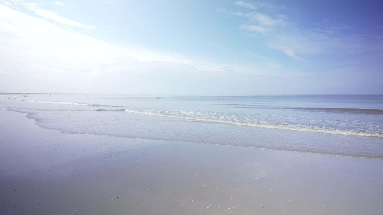 Gentle waves reaching the beach, wide angle panning shot