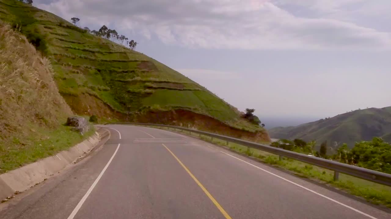 View from a vehicle moving on the road surrounded by beautiful mountains and valley.