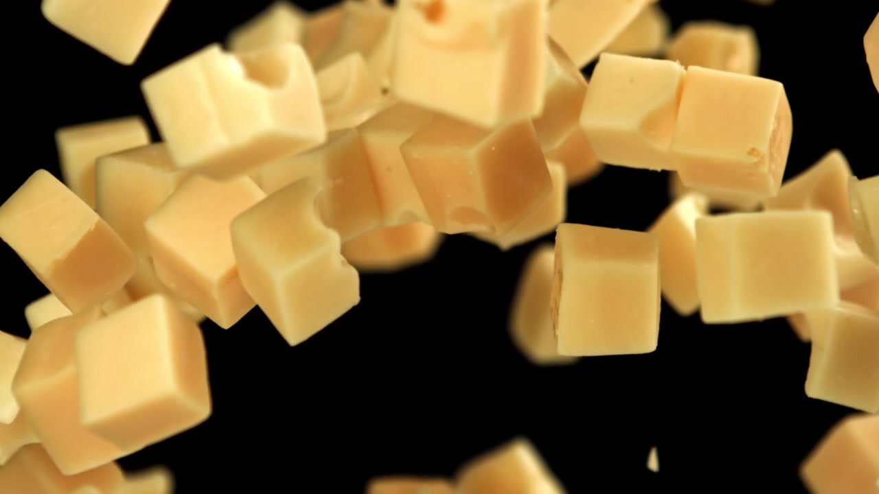 Ralenti de cubes de fromage tombant sur fond noir