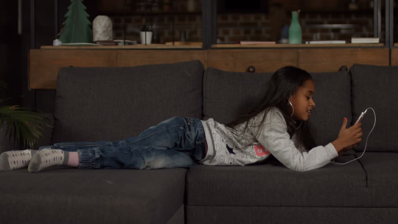 Cute african american girl listening music on couch