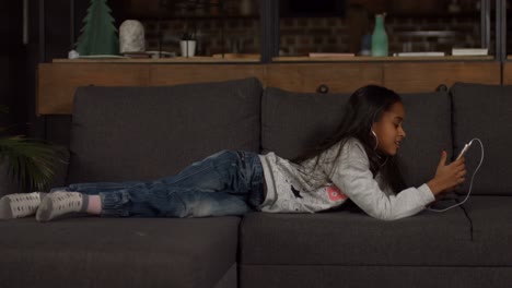 cute african american girl listening music on couch