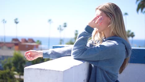 una joven y bella modelo rubia con chaqueta deportiva y capucha en la playa