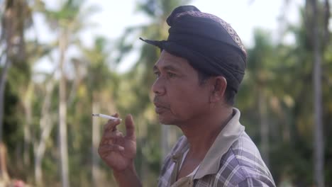 Toma-De-Retrato-De-Un-Hombre-Balinés-Tradicional-Fumando-Un-Cigarrillo-En-Cámara-Lenta