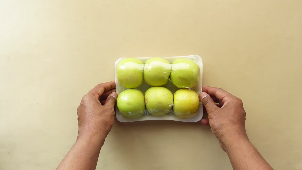 손은 녹색 사과를 들고 있다.