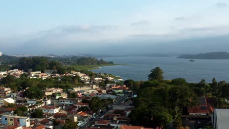 Aerial-drone-dolly-in-shot-of-the-Interlagos-neighborhood-in-the-south-of-São-Paulo,-Brazil-with-the-man-made-Guarapiranga-Reservoir-with-calm-waters,-trees,-and-marinas-in-the-background