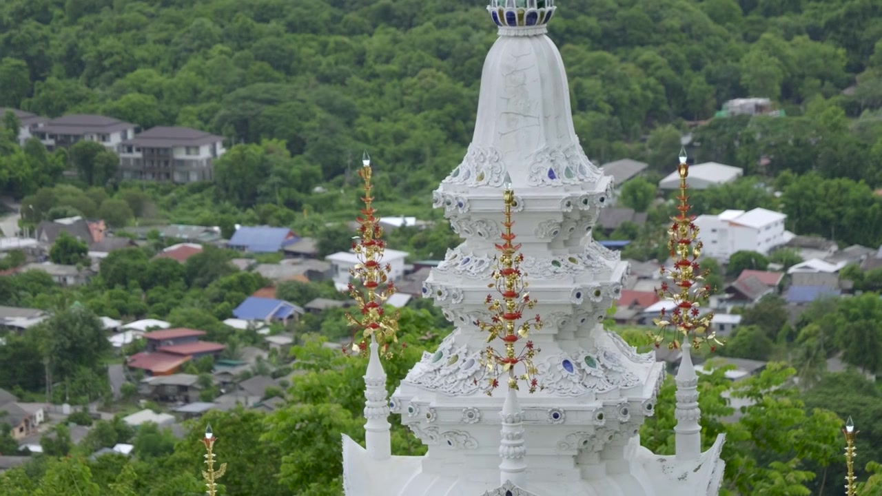 Atap putih menara di kuil Thailand dengan kota di kejauhan.