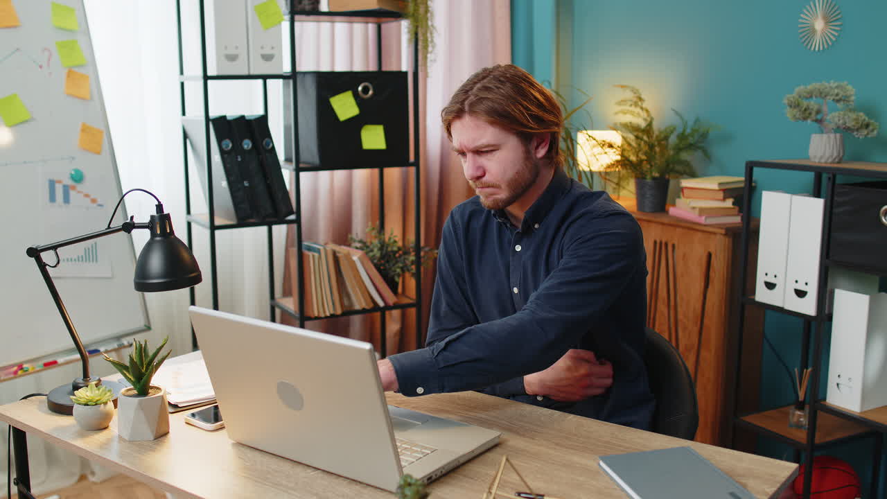 Upset business man feeling stomach ache overeating during work process on laptop in home office