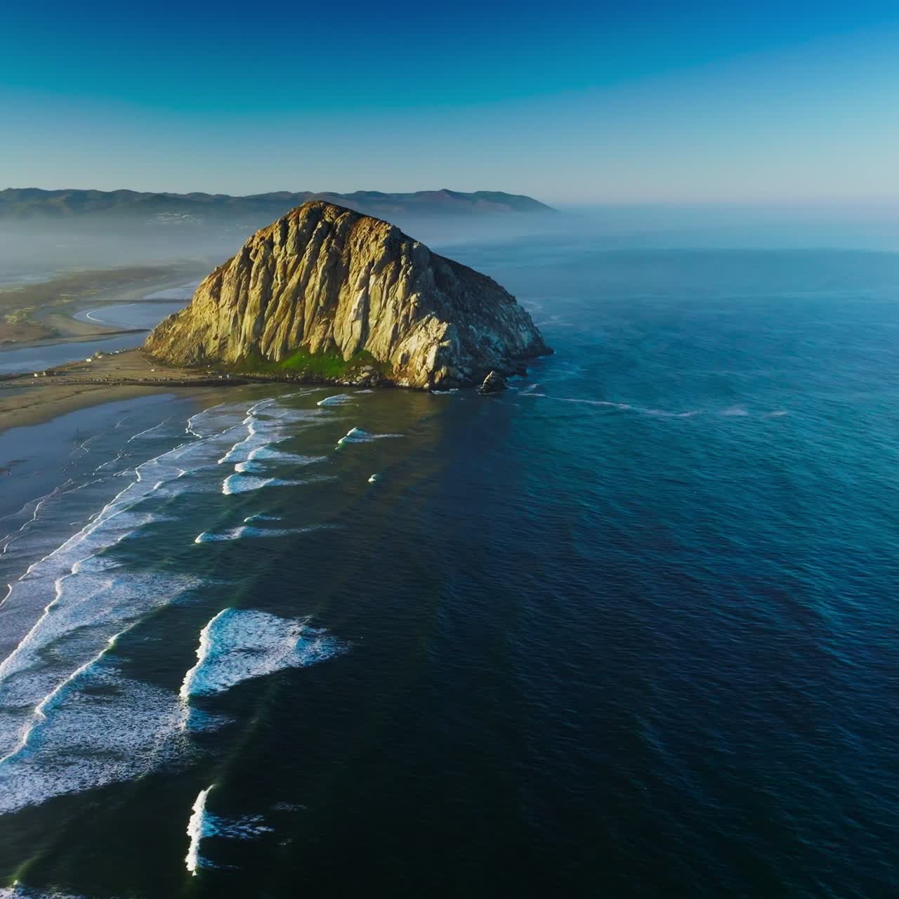 Splendid scenery of Pacific Ocean coastline with huge rock on the beach. White foamy tides coming to the shore