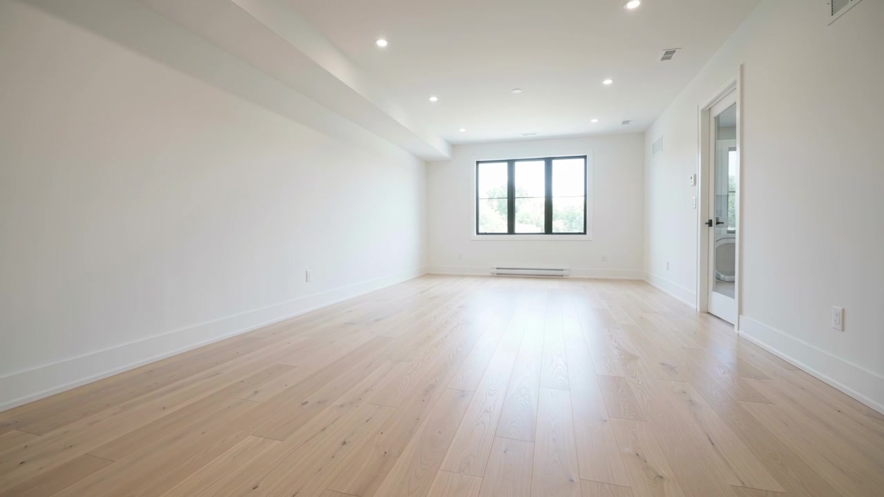 Slowly panning camera approaching far wall in finished room, showcasing window, heater, doorway