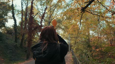 a girl taking a photo of a leaf in the park in autumn, montpellier - france, close shot