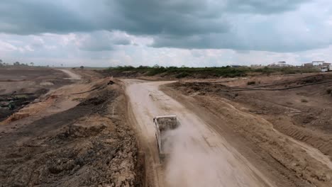 camión de descarga conduciendo en el camino de tierra polvoriento al sitio de minería de carbón