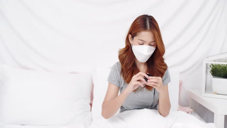 Asian-woman-with-mask-measuring-blood-oxygen-saturation-level-with-pulse-oximeter-at-home-during-the-COVID-19-pandemic-and-self-quarantine