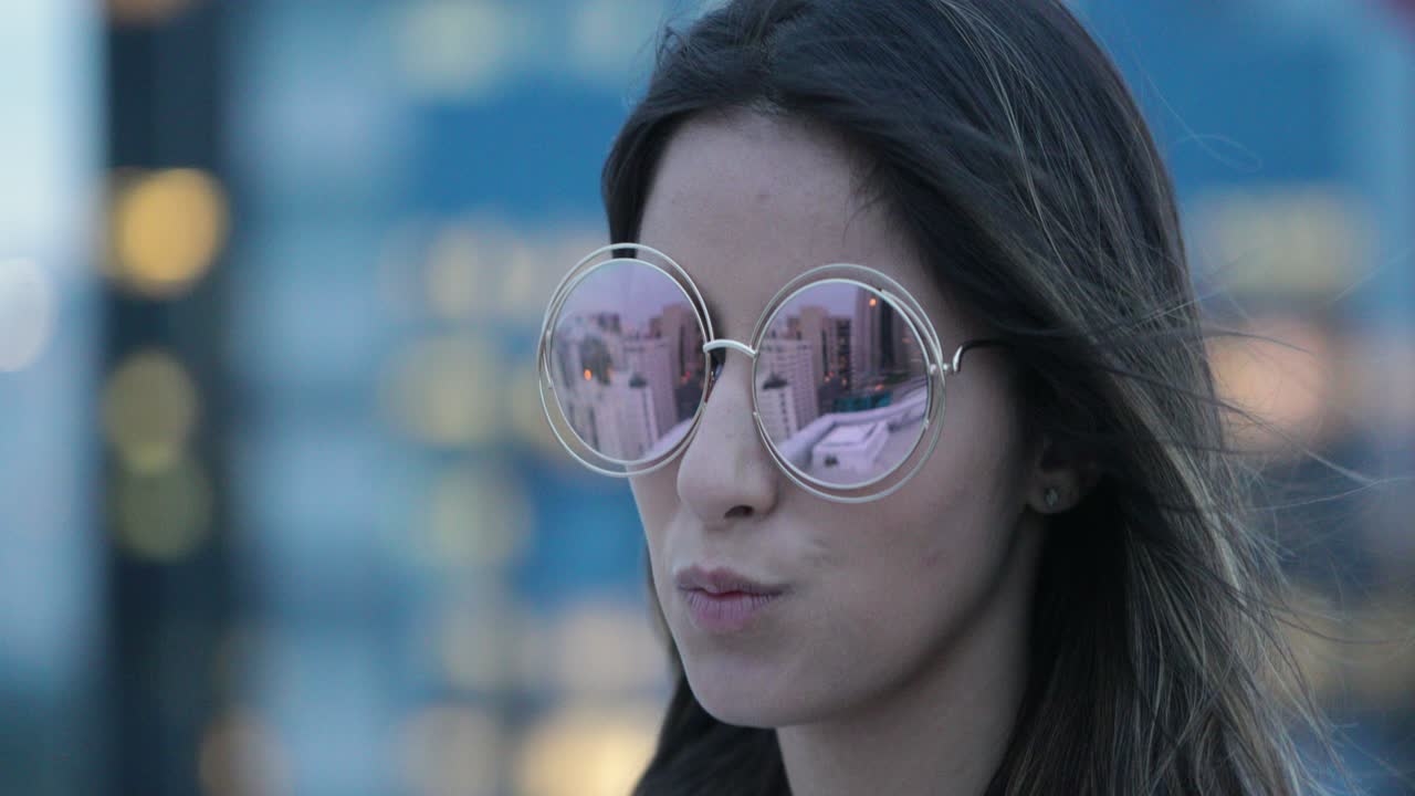 chica posando con gafas de sol grandes y redondas por la noche