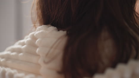 person wears plush robe making procedure in shower. brunette woman runs hand with electric device over face in modern bathroom back view slow motion