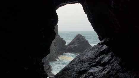 cornwall crantock view of rough sea and rocks through a cave window close up