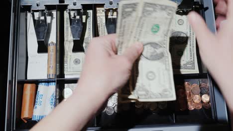 a woman cashier works with the cashier. he puts money and takes the change. trading for cash