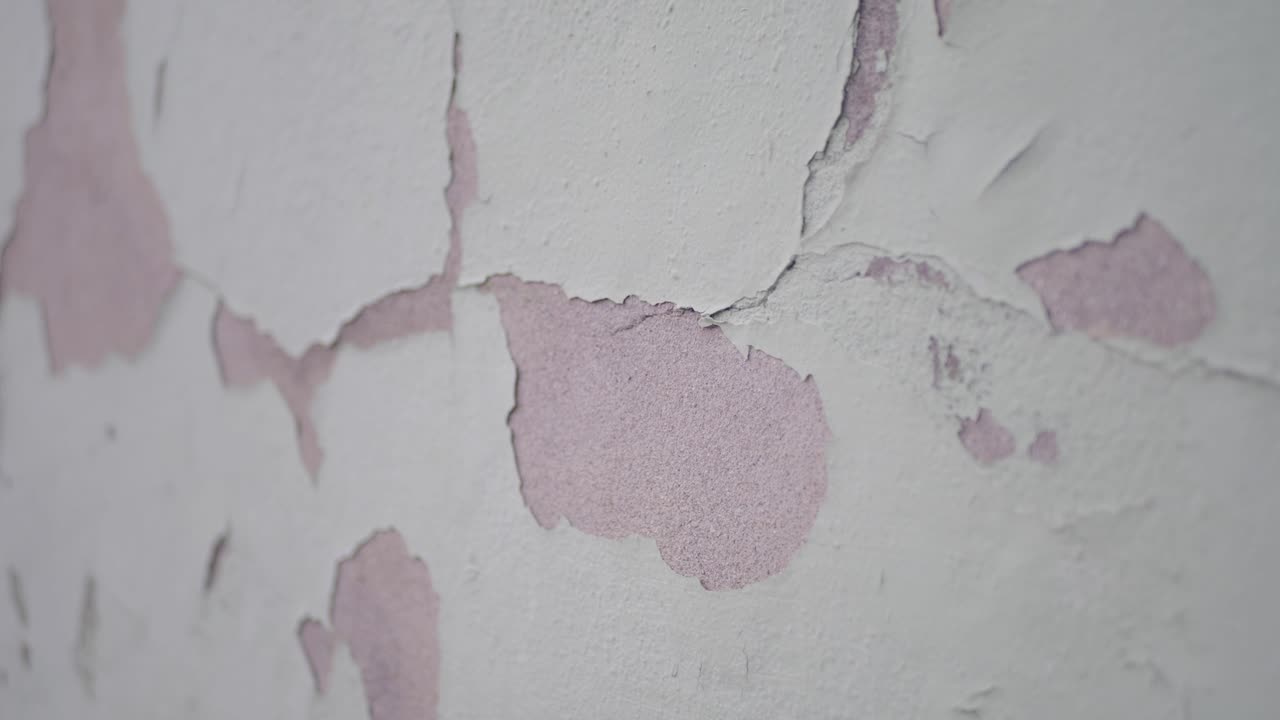 Close-up of Peeling White Paint on a Damaged Wall