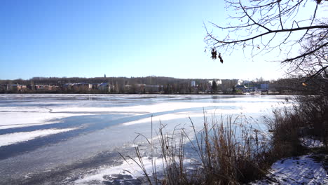 still shot of a frozen lake with cars and smoke in the back