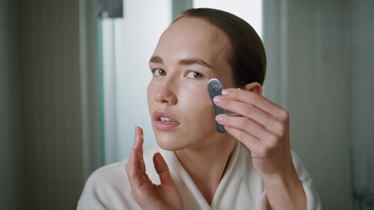 Girl massaging ideal skin with gua sha therapy closeup. lady lifting