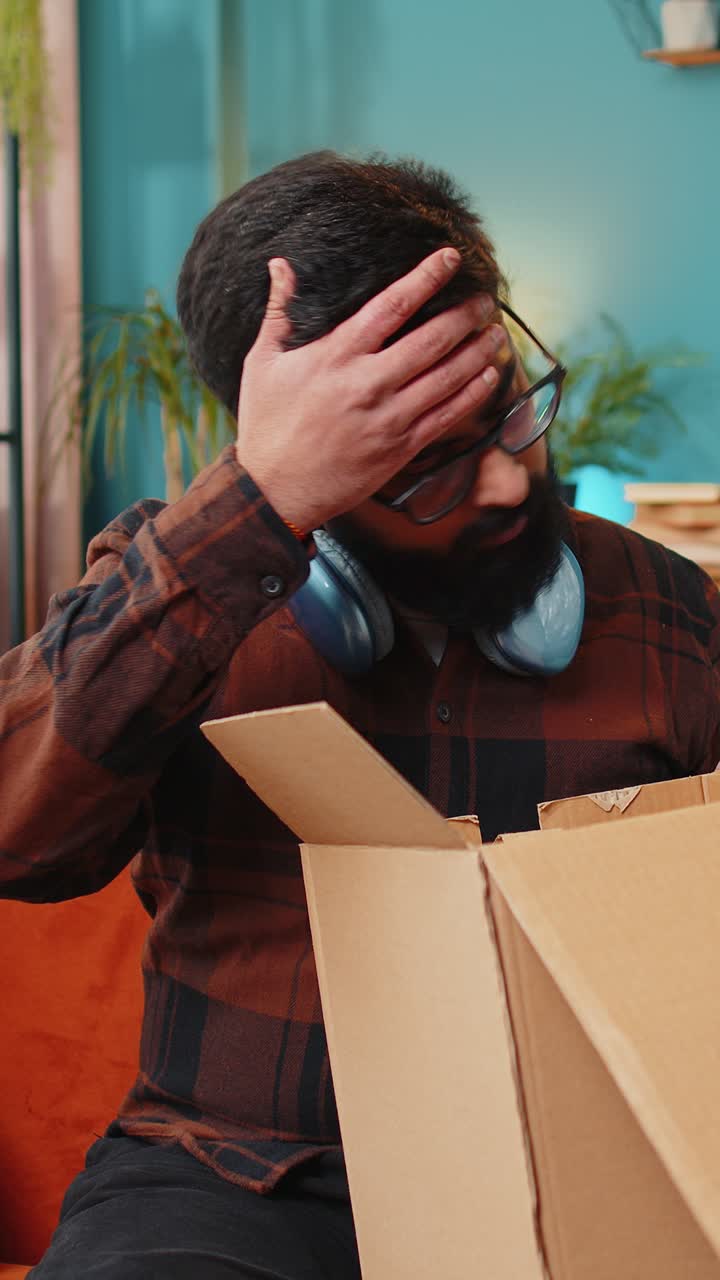 Cliente indiano arrabbiato e insoddisfatto che disimballa un pacco, contrariato e confuso per la consegna sbagliata