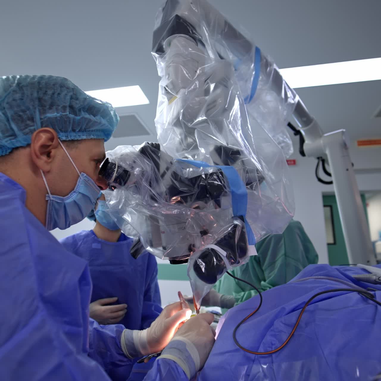 Doctor carefully applying the instruments in the patient's cut and the process is shown at the screen. Neurosurgeon looks intently in the microscope at surgery