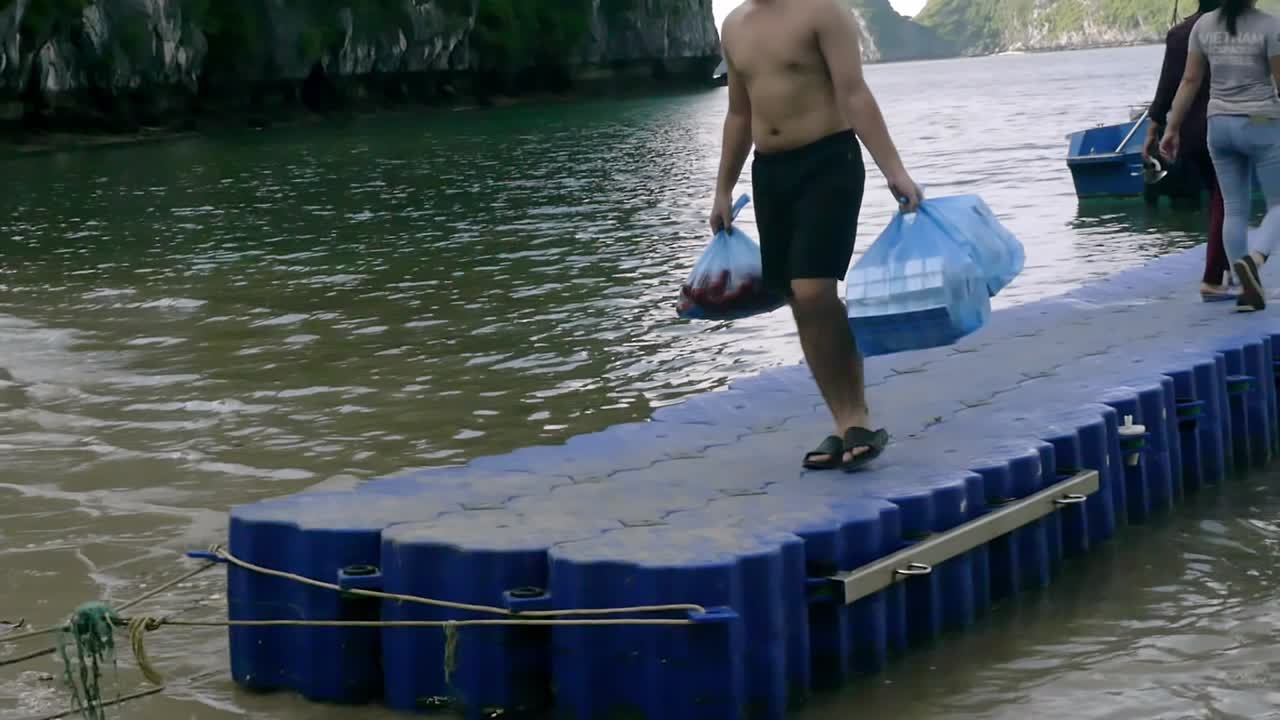 Man Carrying Bags on Floating Dock near Tropical Island