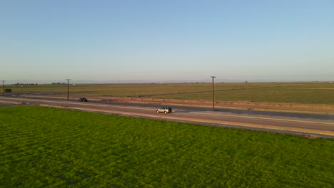 a car driving in the dirt next to the highway in imperial valley during sunset