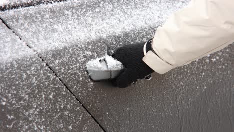 hand pulling frozen car door handle to open