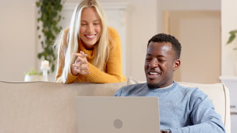 diverse couple enjoying cozy conversation at home with laptop, sharing joyful moments