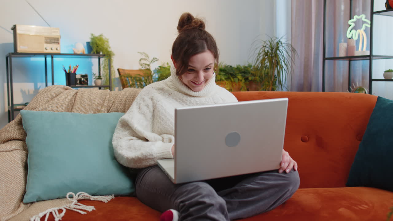 Woman sitting on home couch looking at camera making video conference call with friends or family