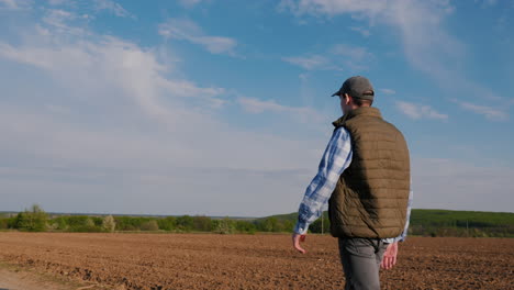 farmer walking through plowed field on a sunny day