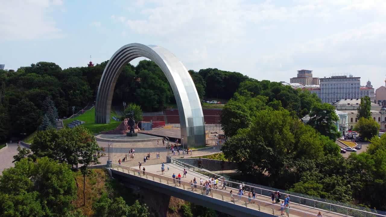 우크라이나 수도의 보행자 다리 근처에 거대한 무지개 모양의 아치 기념물을 드러내기 위해 천천히 올라가는 드론
