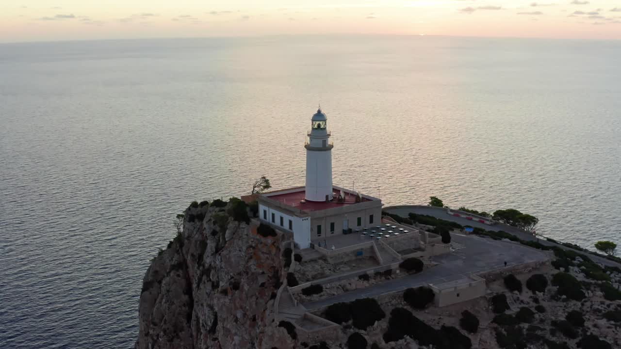 Vecchio faro storico sul bordo di una scogliera a picco sul mare alla luce del tramonto, ripresa aerea con drone