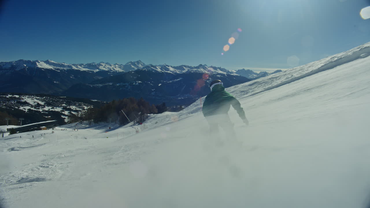 Snowboarder che scende su una pista blu battuta ad Anzère in una giornata di sole splendente, eseguendo fluidamente un butter 360 su un dosso. Luce alpina pulita, azione freestyle dinamica, un momento cinematografico di sport invernali.