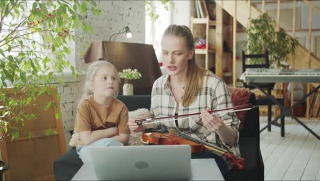 mom and daughter learn to play the violin in the video from the internet
