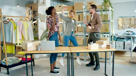 diseñadoras de ropa y sastre bailando en un taller divirtiéndose, sintiéndose feliz y celebrando la apertura de la tienda