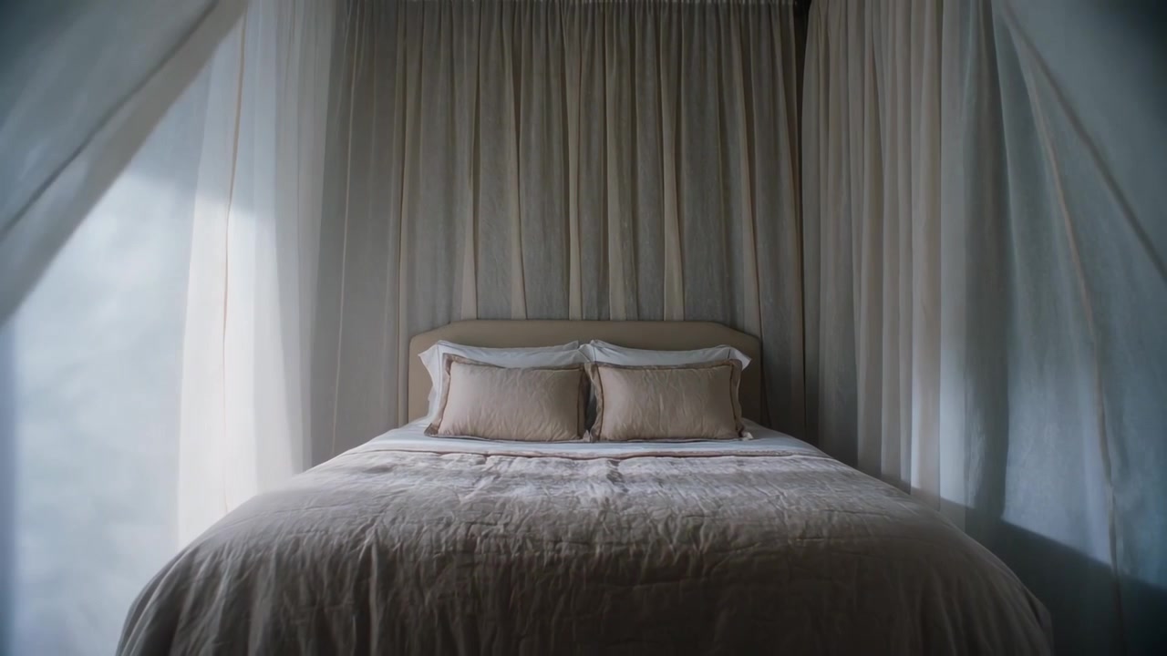 Cucitura che si apre rivelando un letto a baldacchino in camera da letto, con pannelli trasparenti e piumone che lasciano entrare una luce soffusa.