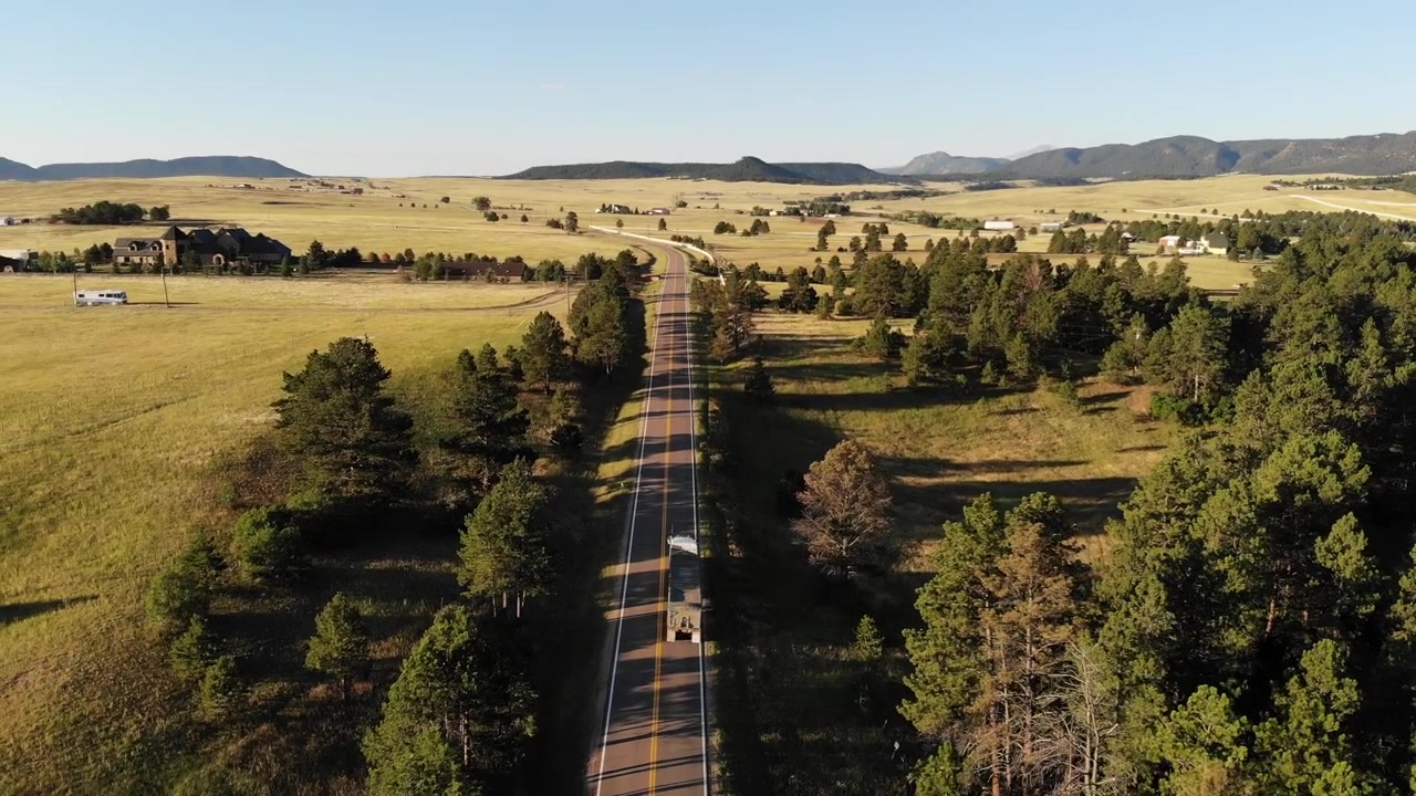 A reverse pan over a country road on a spring morning as a truck makes its way south