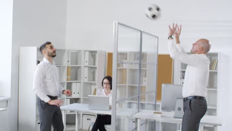 two colleagues tossing ball across office partition