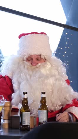 Santa Claus Enjoys a Casual Moment with Beer Blending Holiday Cheer a Man in a Santa Claus Suit Enjoys a Casual Moment at a Table full of Beer Blending Holiday Cheer with Humor as he Takes a Break