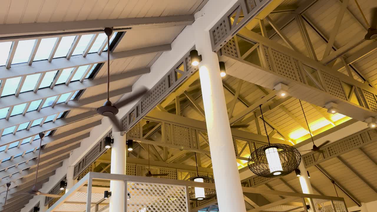 una serie de marcos que muestran una estructura de techo moderna con claraboya y vigas, con iluminación cálida y diseño geométrico