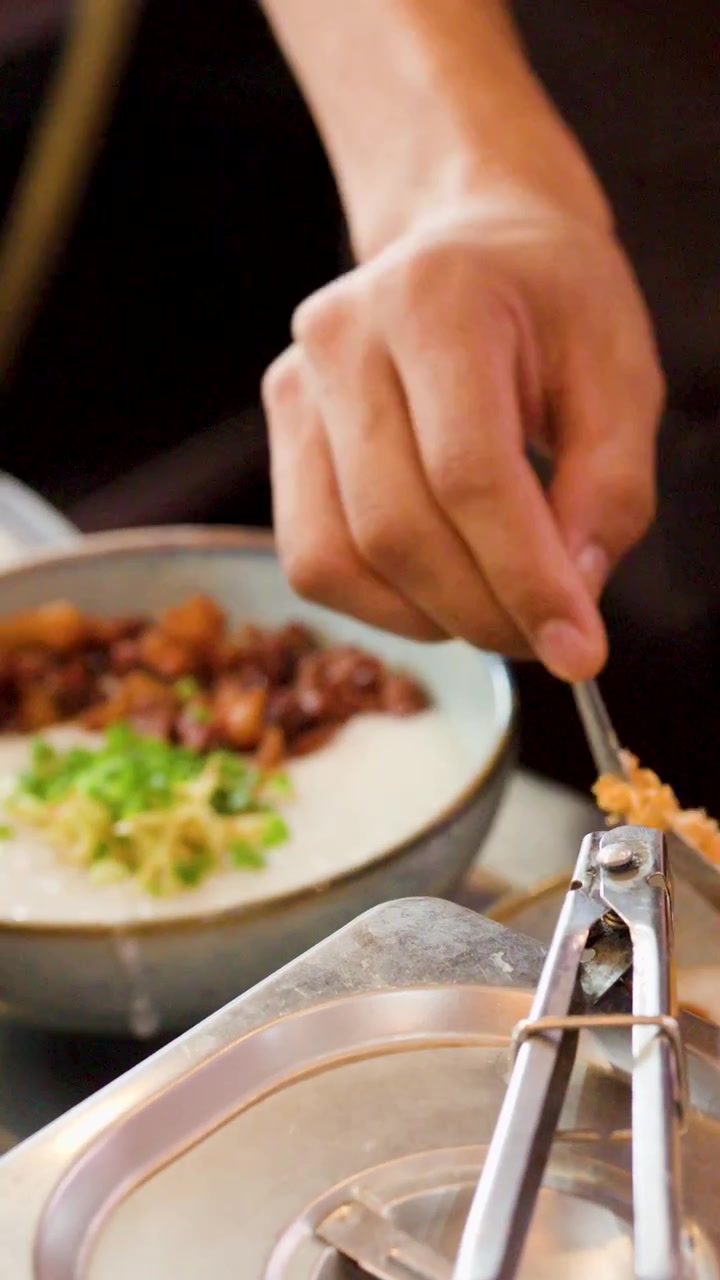 Chef Adding Crispy Toppings to a Bowl of Congee