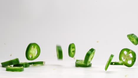 Sliced-jalapeño-coins-falling-and-bouncing-on-white-studio-backdrop-in-4k-slow-motion