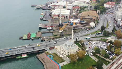 drone aéreo de automóviles y autobuses que cruzan el puente y la carretera de ataturk durante una mañana nublada en estambul, turquía, con una mezquita en la costa del río bósforo