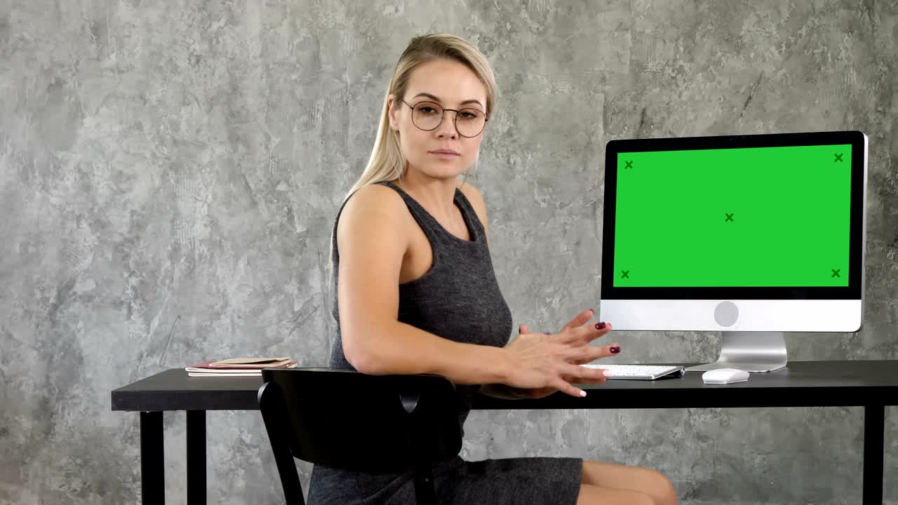 Proud freelance woman posing at office and looking at you. View to computer screen. Green Screen Mock-up Display