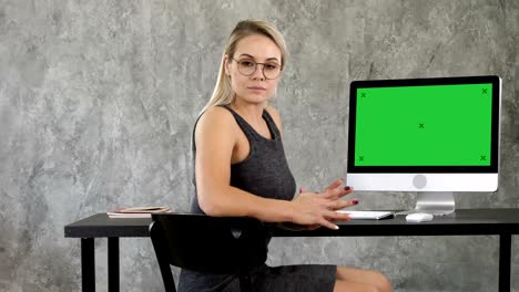 proud freelance woman posing at office and looking at you. view to computer screen. green screen mock-up display