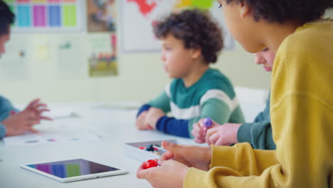 estudiantes de primaria en el aula estudiando modelos moleculares en la clase de ciencias con tableta digital
