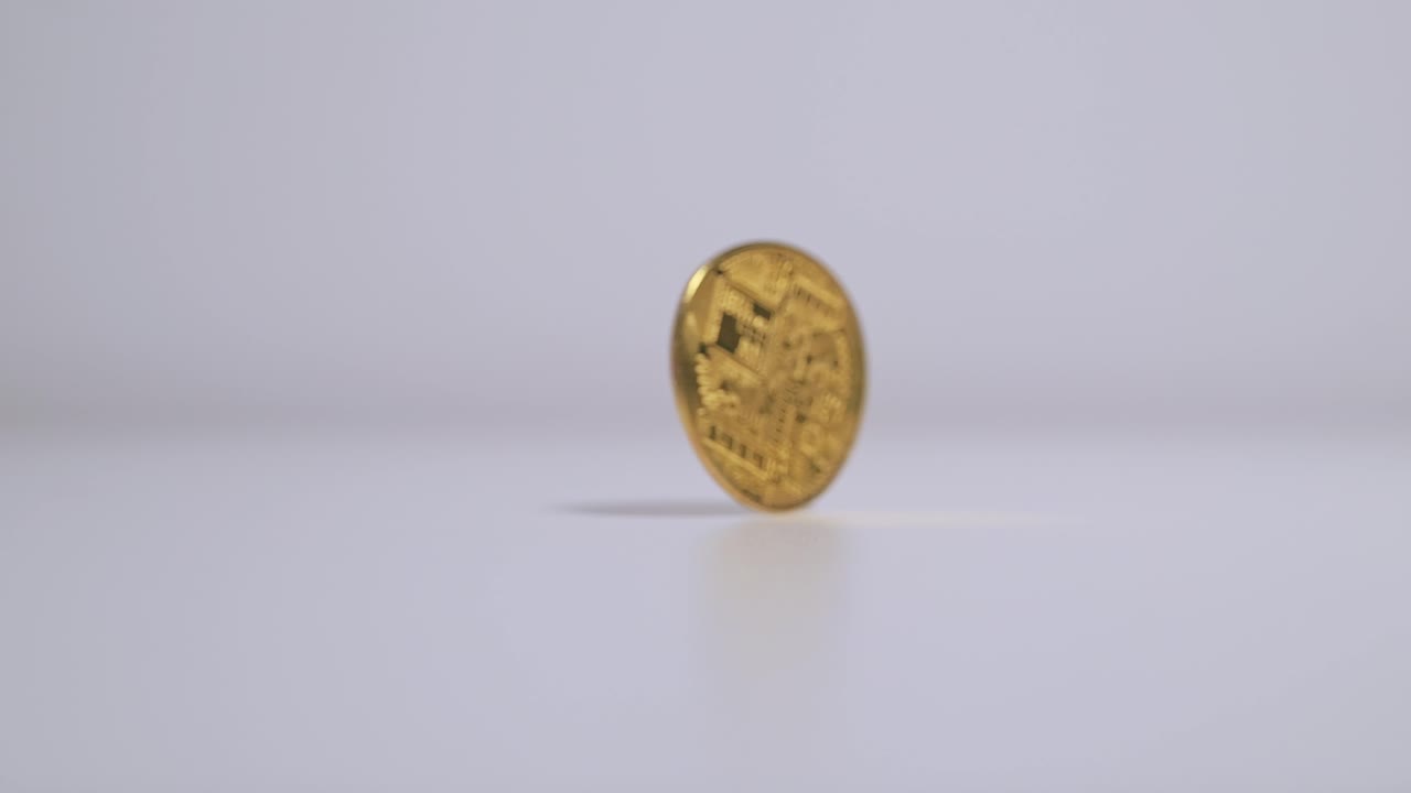 Close-up slow motion, gold Bitcoin spinning from finger flick then falling flat