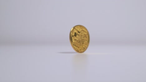 close-up slow motion, gold bitcoin spinning from finger flick then falling flat