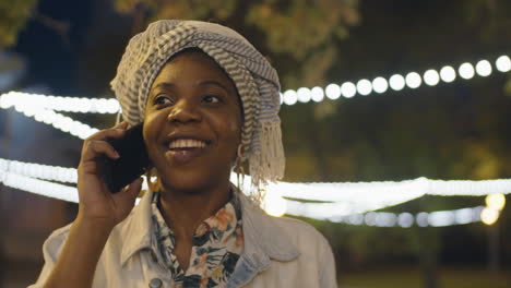 african american woman speaking on phone outdoors in evening